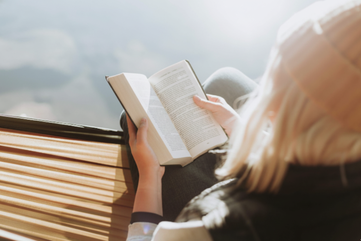 Людина читає книгу на природі, тримаючи її в руках